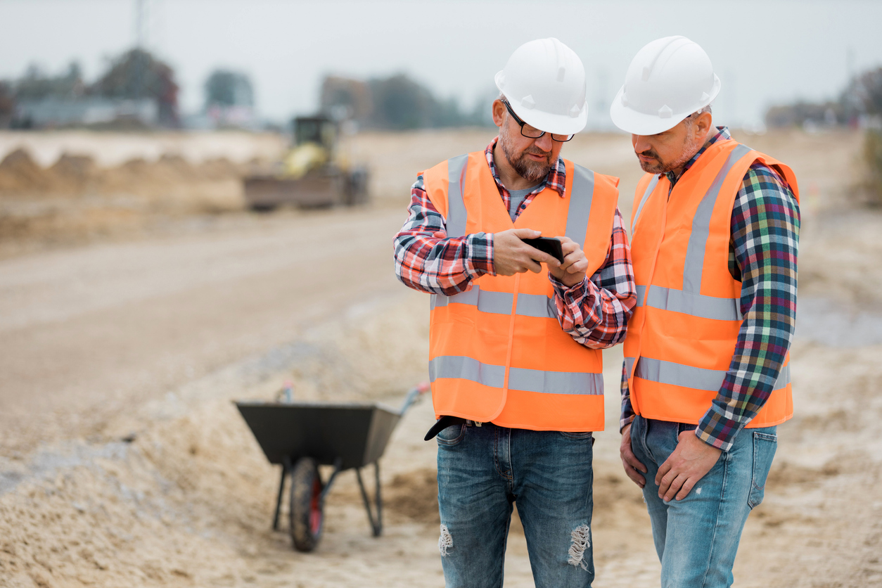 Two builders checking road construction plan